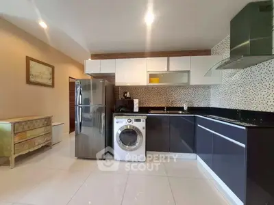 Modern kitchen with sleek cabinets, stainless steel appliances, and washing machine.