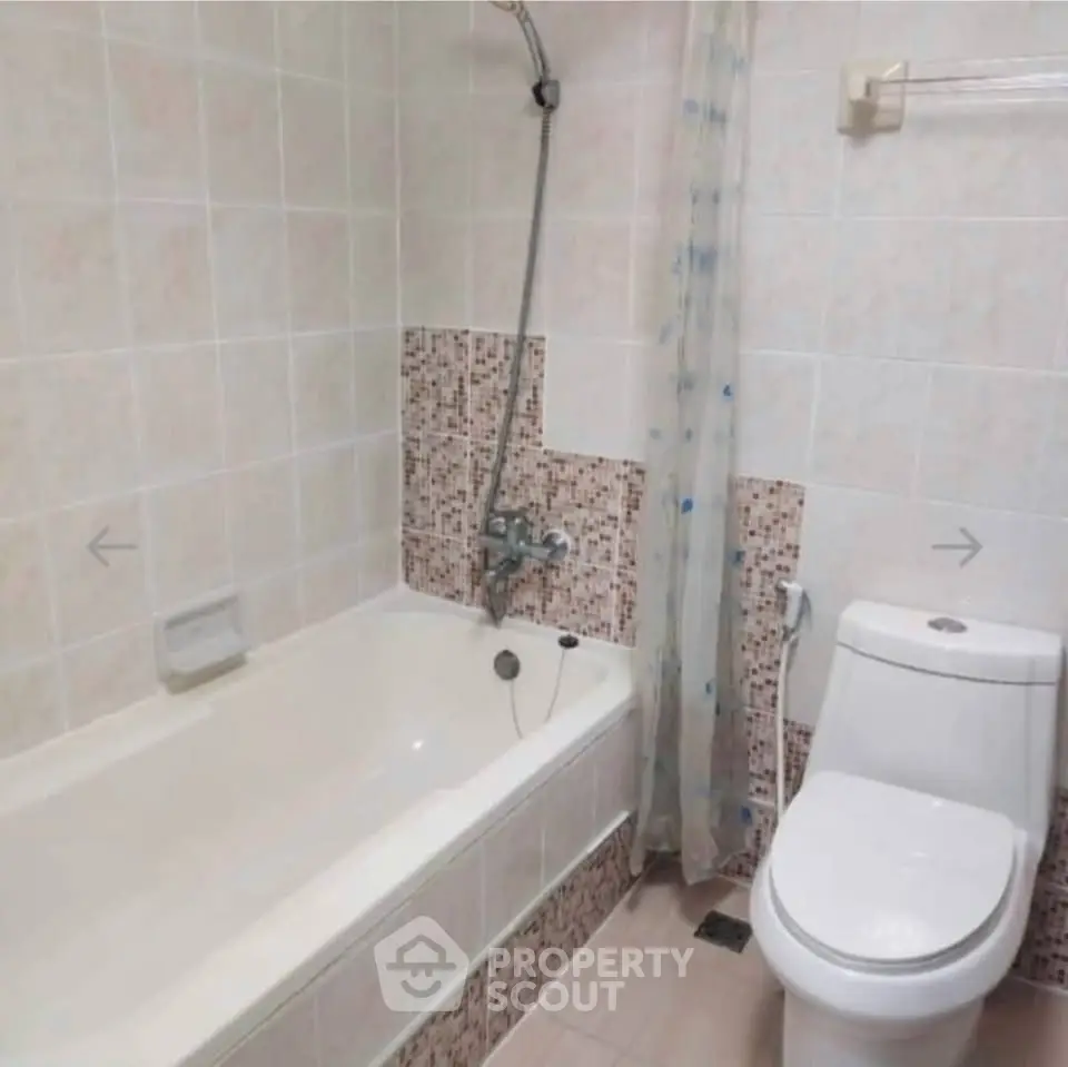Spacious bathroom with bathtub and modern fixtures in a tiled setting.