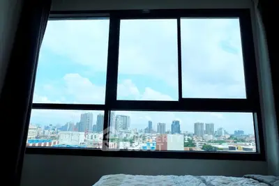 Stunning cityscape view from a modern bedroom window, showcasing urban skyline and blue skies.