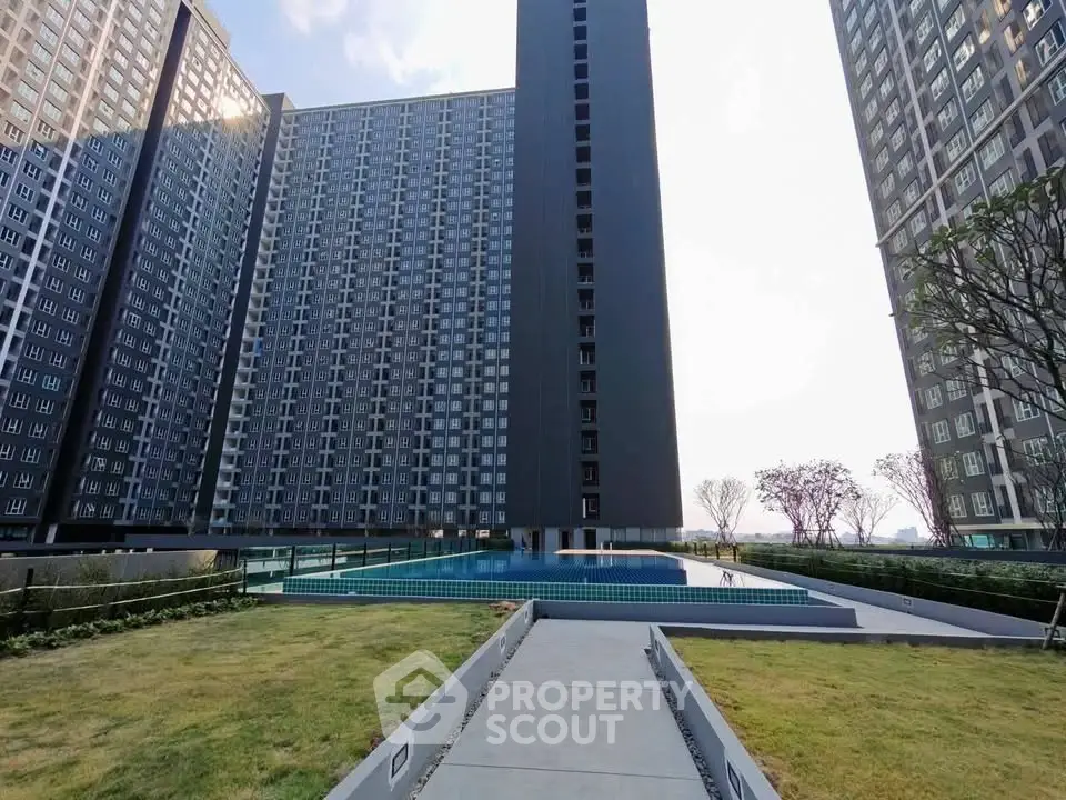 Modern high-rise apartment complex with central swimming pool and landscaped garden.