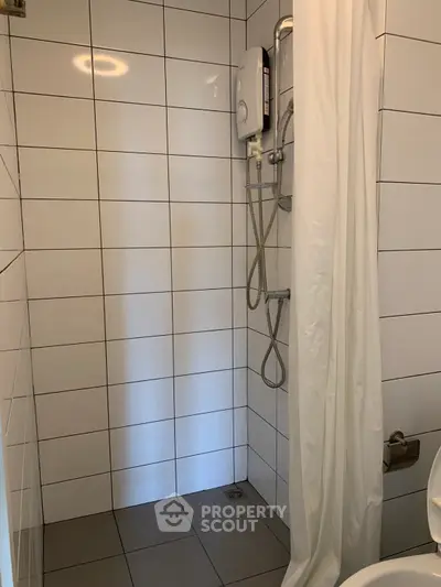 Compact bathroom with tiled shower area and curtain
