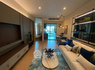 Elegant living room with modern furnishings, plush sofa set, and sleek entertainment unit leading to a sunlit balcony.