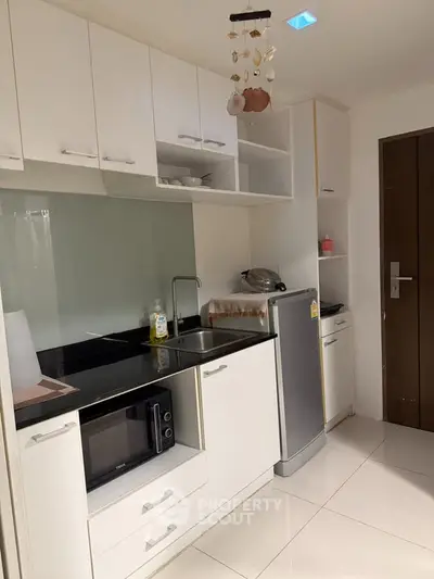 Modern compact kitchen with sleek white cabinets and appliances, perfect for urban living.