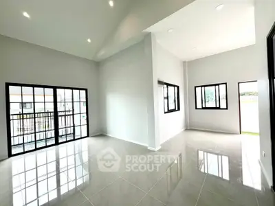 Spacious modern living room with large windows and glossy tiled floors