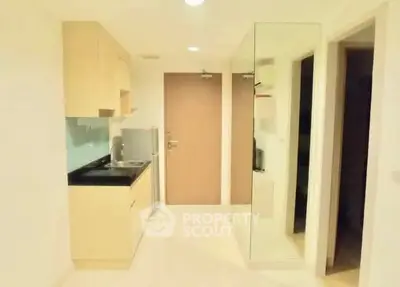 Compact modern kitchen with sleek cabinetry and mirrored wall in a cozy apartment.