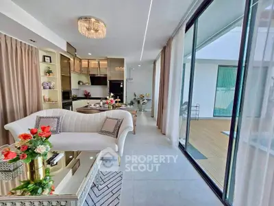 Luxurious open-plan living room with elegant decor and large glass doors leading to a spacious balcony.