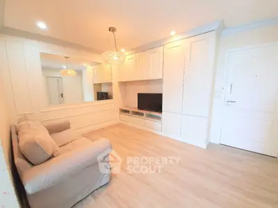 Elegant living room with chandelier, built-in TV unit, and cozy sofa in a bright, modern apartment.