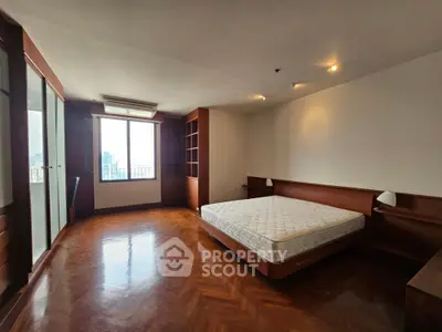 Spacious bedroom with large window and wooden flooring in modern apartment