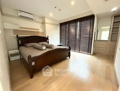 Spacious bedroom with wooden flooring and large windows in modern apartment