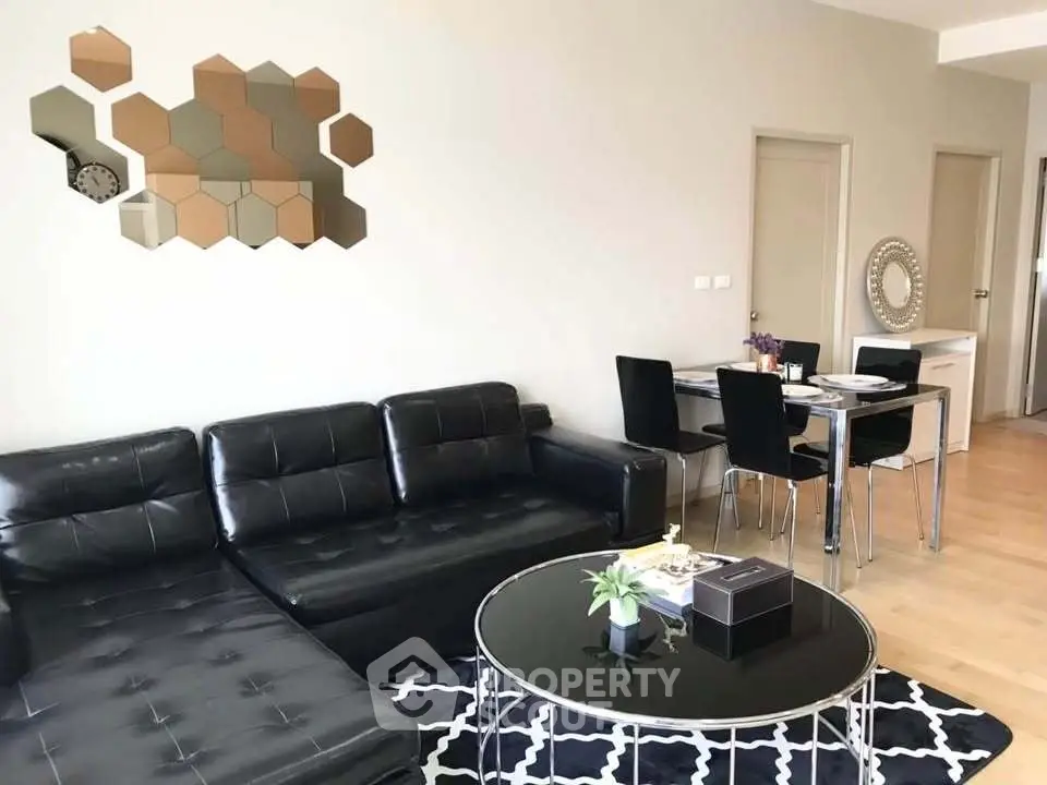 Modern living room with black leather sofa, stylish dining area, and geometric wall decor