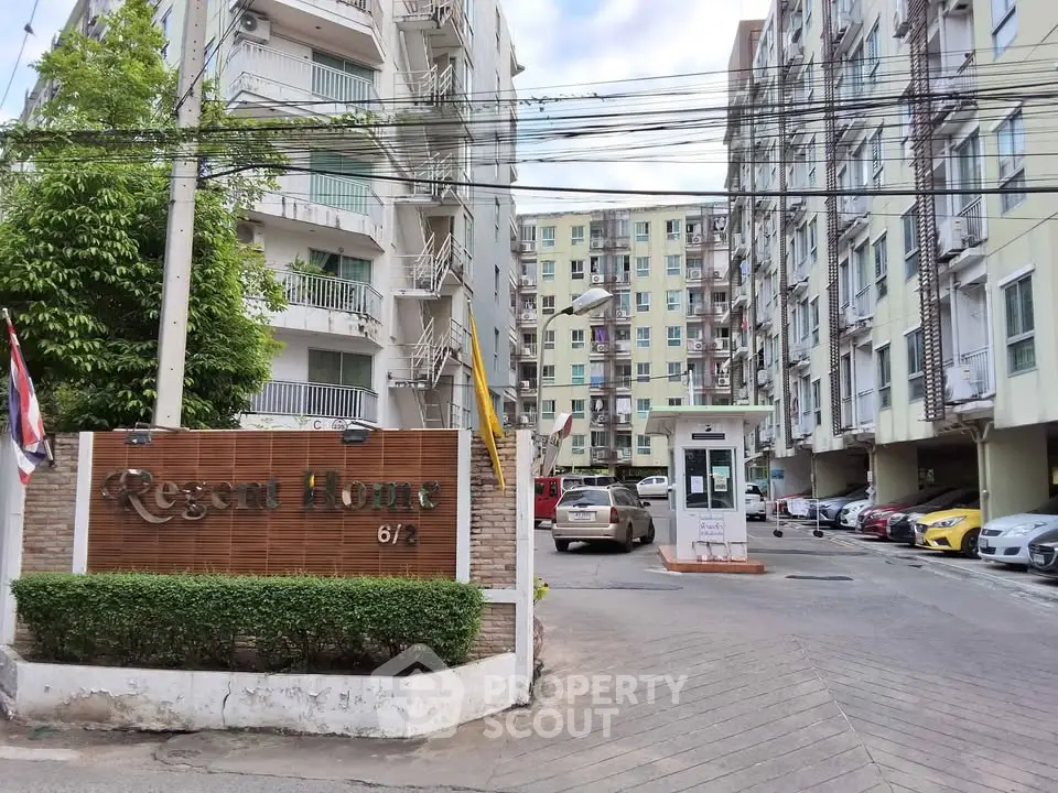 Modern apartment complex entrance with parking and security booth