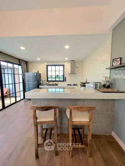 Modern kitchen with open layout and stylish bar seating, featuring sleek appliances and ample natural light.
