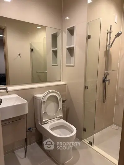 Modern bathroom with glass shower and sleek fixtures in contemporary apartment.