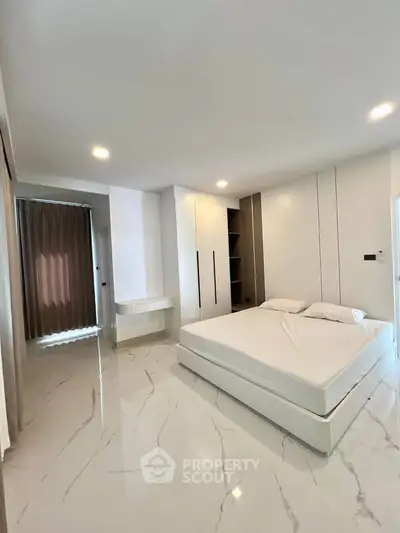 Spacious modern bedroom with sleek design and ample natural light.