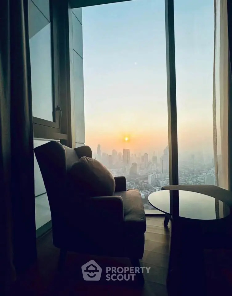 Stunning city view from a modern high-rise apartment with cozy seating area at sunset.