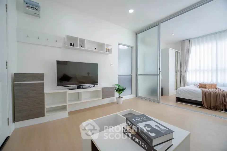 Modern living room with sliding glass doors leading to a cozy bedroom, featuring stylish decor and natural light.
