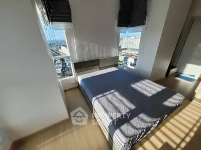 Bright bedroom with large windows and city view, featuring modern decor and wooden flooring.
