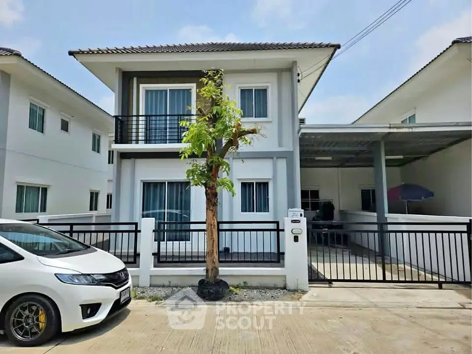 Modern two-story house with carport and gated entrance in a suburban neighborhood.