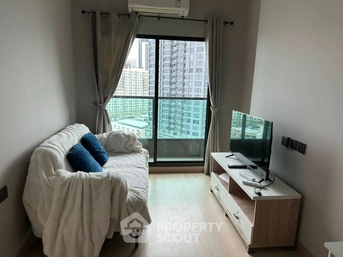 Cozy living room with city view, featuring a comfortable sofa and modern TV setup.