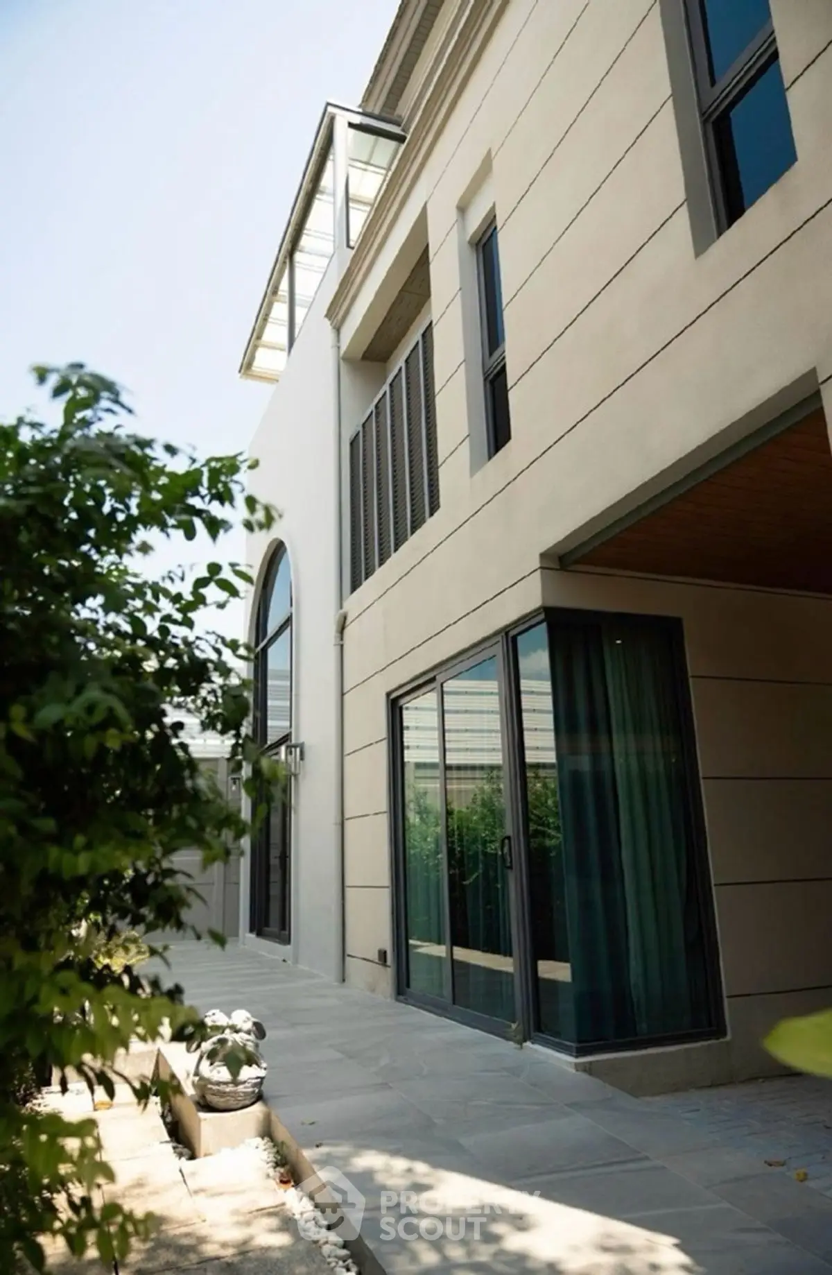 Modern luxury home exterior with large windows and lush greenery