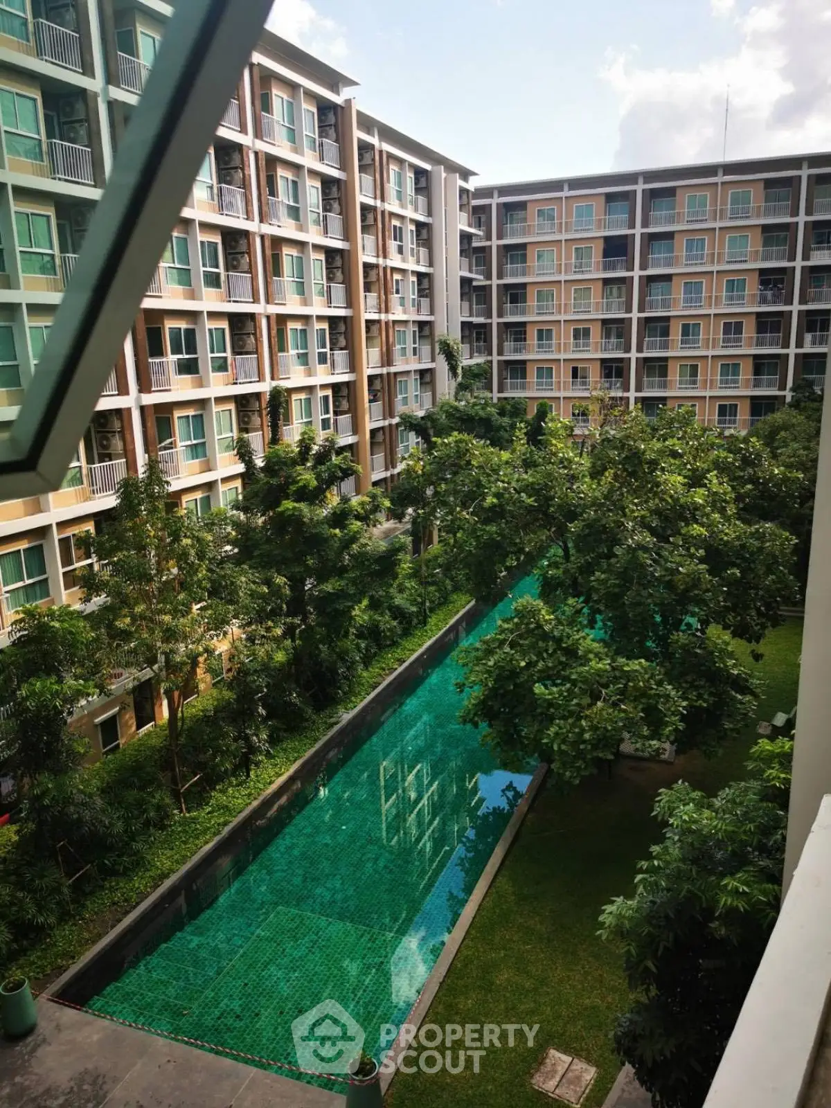 Modern apartment complex with lush garden and inviting swimming pool view.