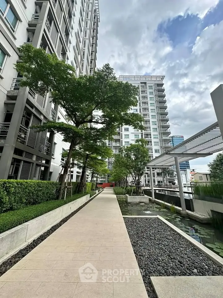 Modern apartment complex with lush landscaping and serene walkway.