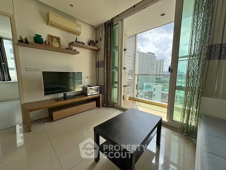 Modern living room with balcony and city view, featuring sleek furniture and natural light.