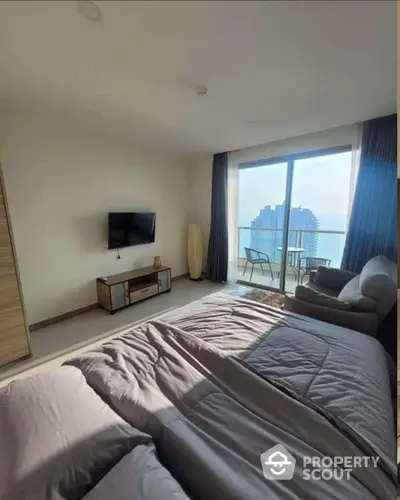 Modern bedroom with balcony and city view, featuring cozy furnishings and natural light.