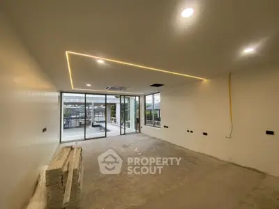 Spacious modern living room with large windows and recessed lighting, offering a bright and airy atmosphere.