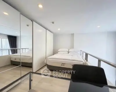 Modern loft bedroom with mirrored closet and sleek desk, featuring a King Koil bed for ultimate comfort.
