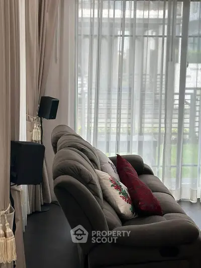 Elegant living room with plush sofa and sheer curtains, offering a cozy and inviting atmosphere.