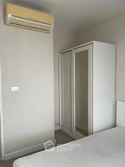 Minimalist bedroom with air conditioning and sleek wardrobe design.