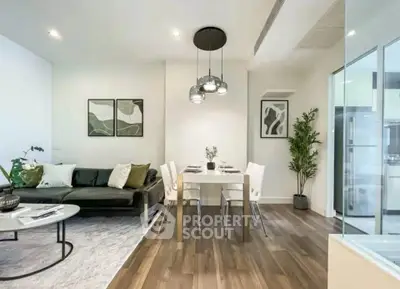 Modern living room with stylish decor and dining area, featuring elegant lighting and wooden flooring.