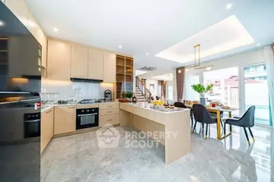 Spacious modern kitchen with open layout and dining area, featuring sleek appliances and elegant decor.