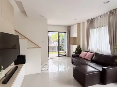 Modern living room with sleek leather sofa and large window overlooking garden