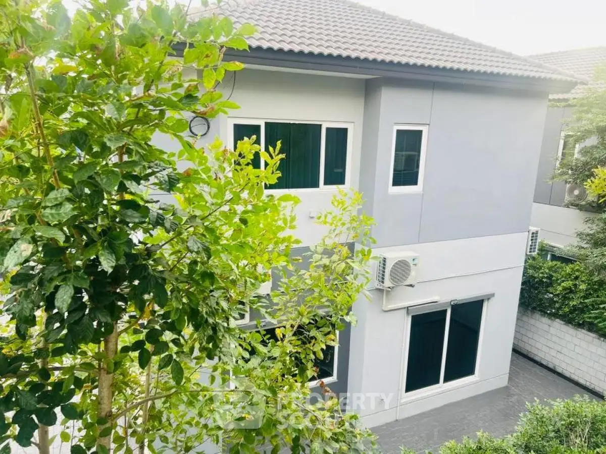 Modern two-story house with lush greenery and air conditioning unit