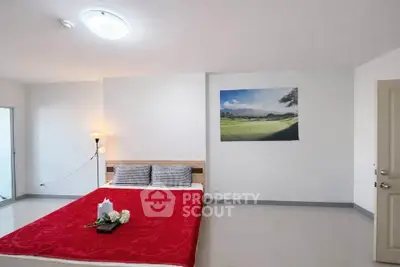 Spacious bedroom with modern decor and vibrant red bedding in a stylish apartment.