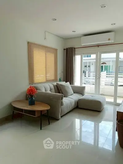 Bright living room with modern sofa and large windows overlooking balcony.