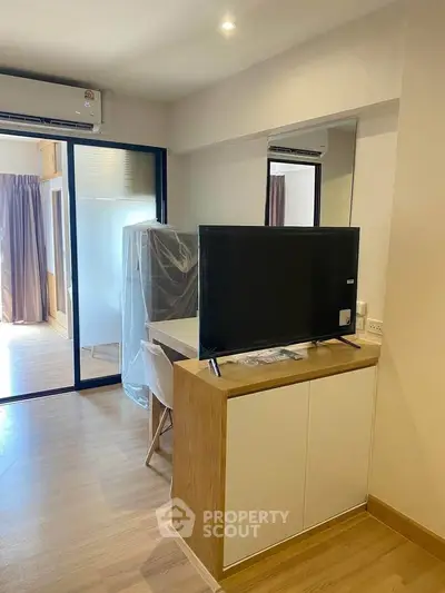 Modern apartment interior with sleek TV stand and air conditioning, featuring wooden flooring and natural light.