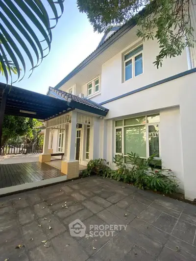 Charming two-story house with spacious patio and lush greenery, perfect for family living.