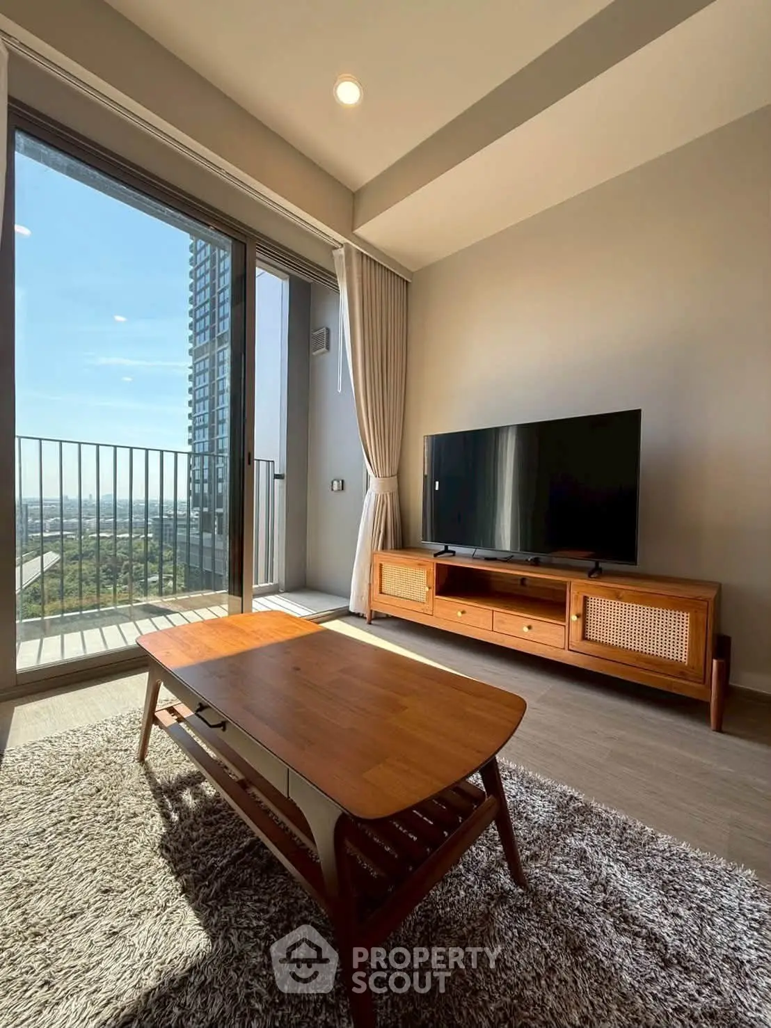 Modern living room with large window and balcony view, featuring stylish furniture and natural light.