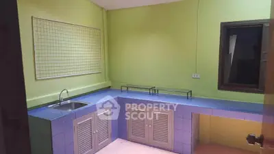 Charming kitchen with vibrant green walls and blue tiled countertops, featuring a sleek sink and ample storage.