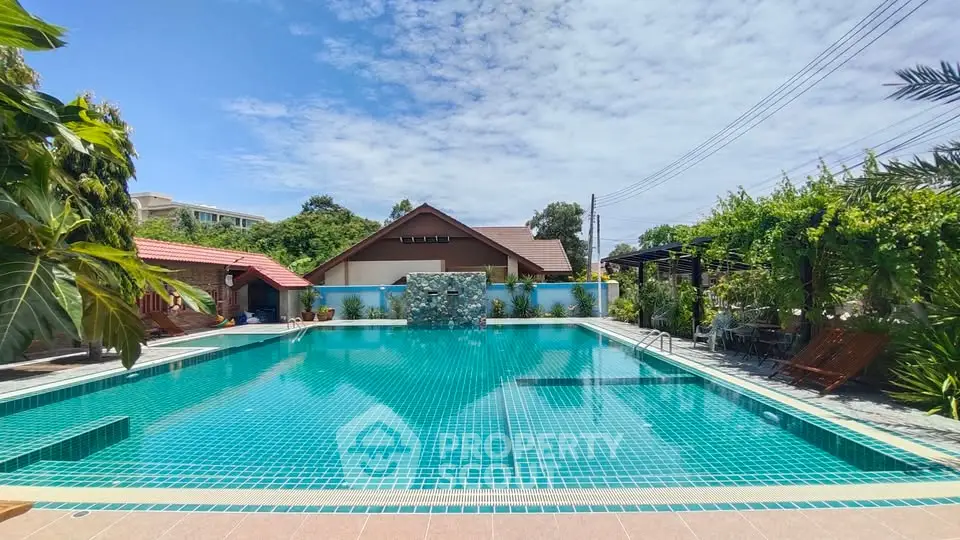 Stunning outdoor pool area with lush greenery and clear blue skies, perfect for relaxation and leisure.