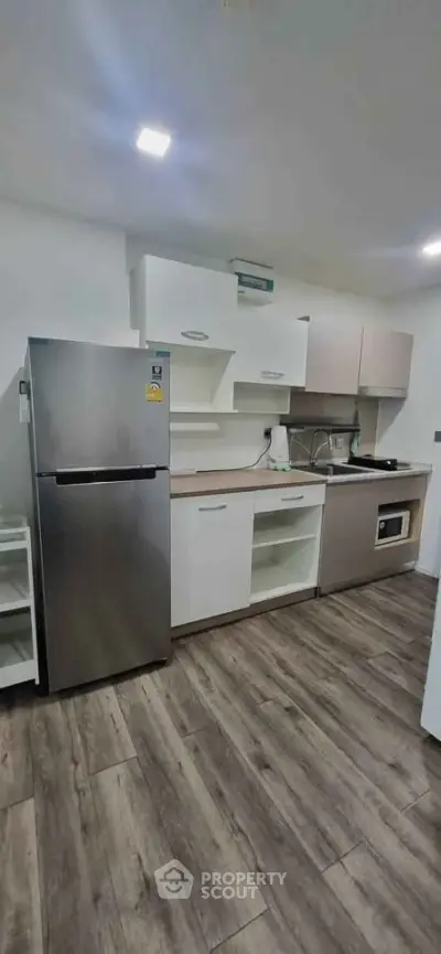 Modern kitchen with sleek appliances and wood flooring in a stylish apartment.
