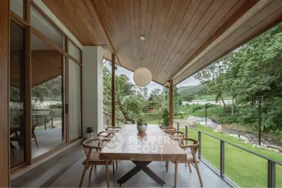 Stunning outdoor dining area with wooden ceiling and lush garden view, perfect for entertaining.