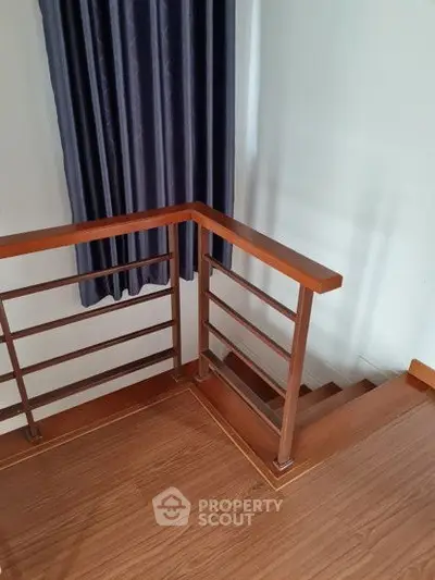 Stylish wooden staircase with modern railing and elegant curtain in a contemporary home.