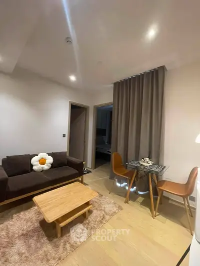 Cozy living room with modern decor and dining area, featuring a plush sofa and stylish chairs.