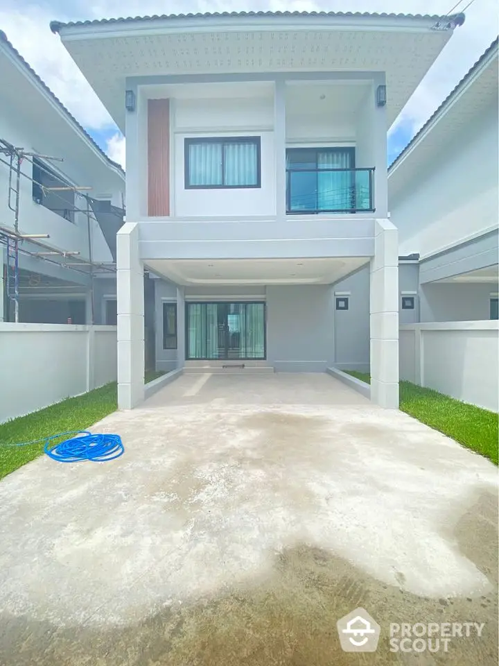 Modern two-story house with spacious driveway and sleek balcony design.