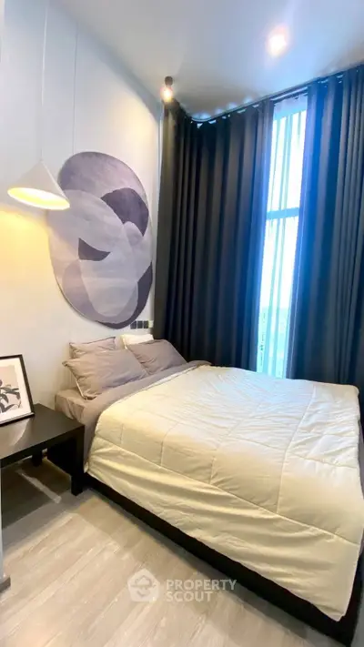 Modern bedroom with stylish decor and large window, featuring cozy bedding and contemporary artwork.