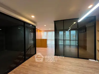 Spacious modern living room with glass partitions and wooden flooring